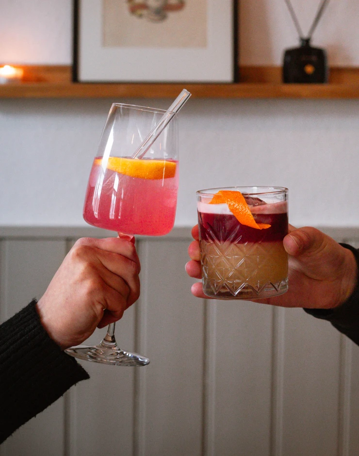 Sarti Spritz & New York Sour Zwei Gäste stoßen mit leckeren Drinks im Innenbereich an