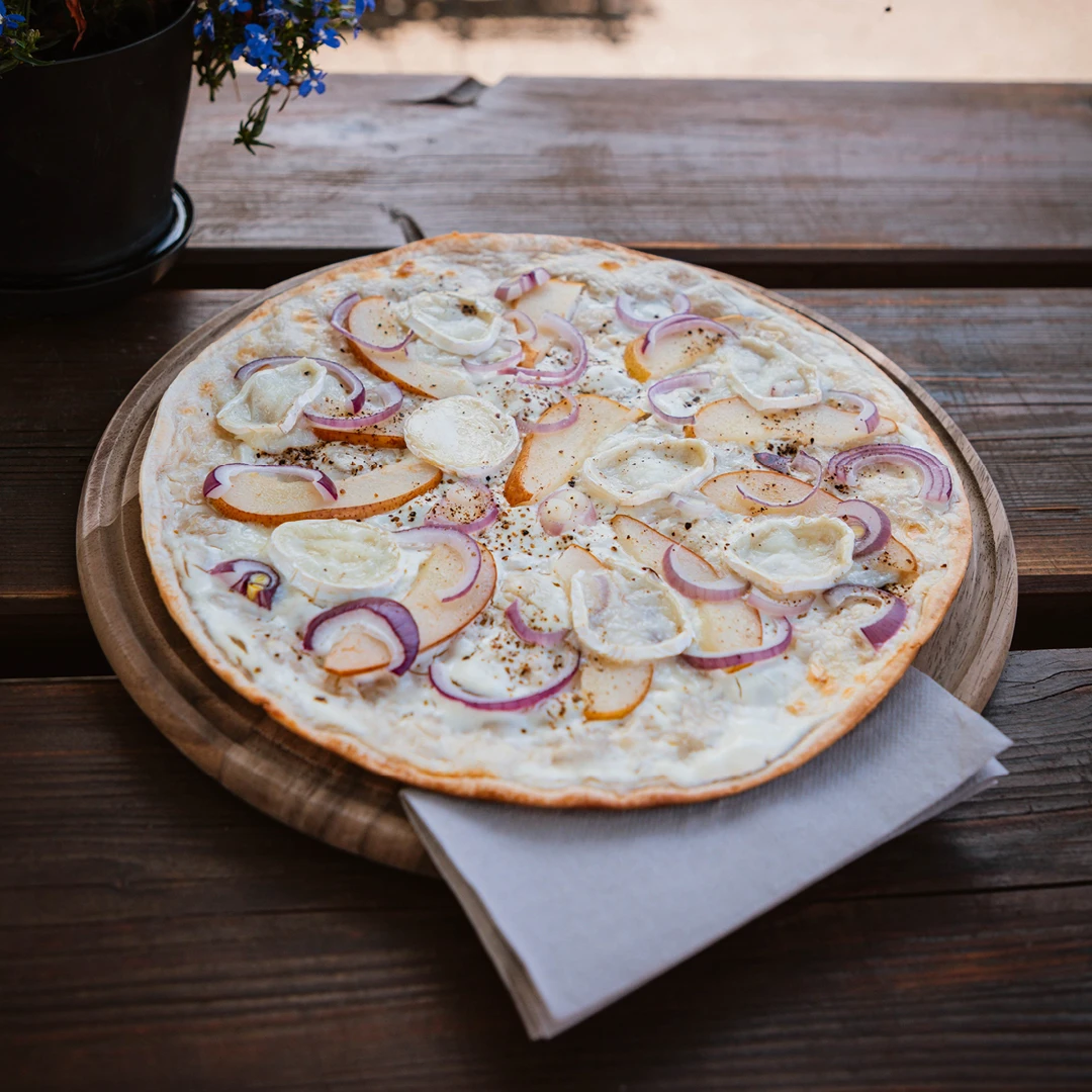 Frisch gebackener Flammkuchen mit Birne, Ziegenkäse und roten Zwiebeln